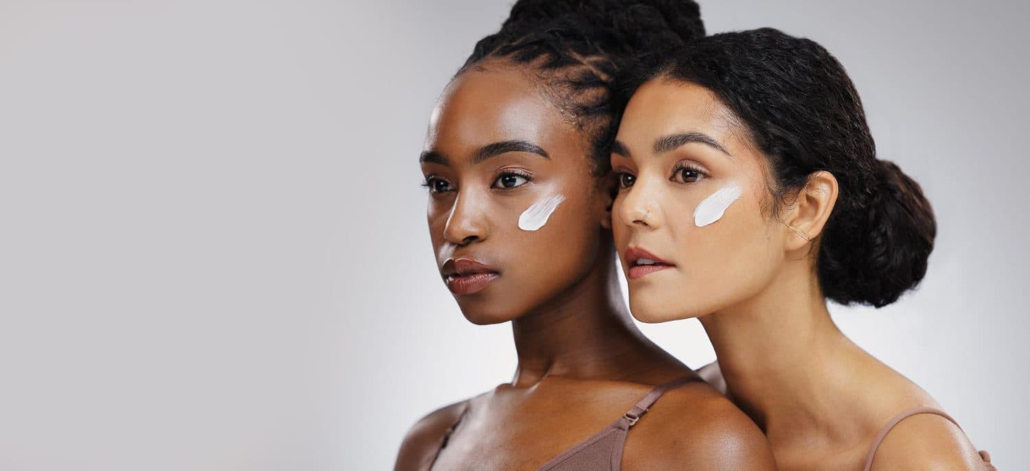Two GLO30 members with skincare applied to their cheeks